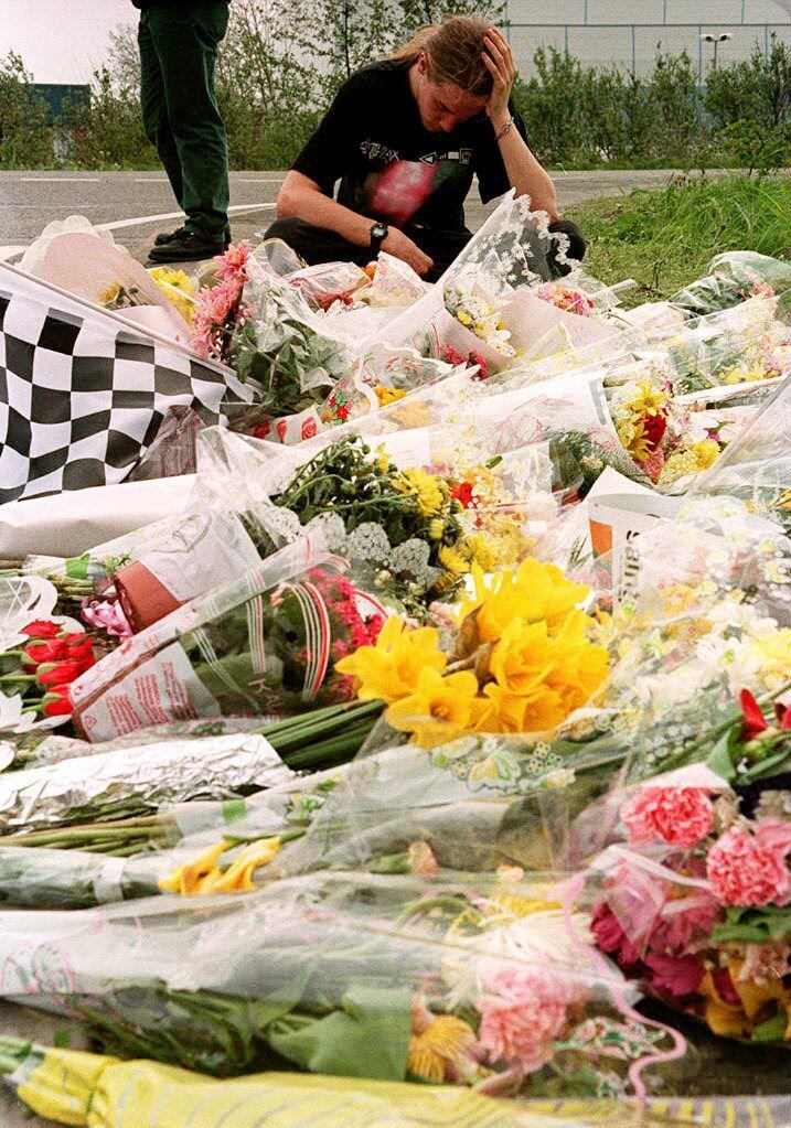 Un joven fanático de Ayrton Senna deja flores en las puertas de la fábrica de Williams-Renault en Didcot, Gran Bretaña, el 3 de mayo de 1994. (AFP)