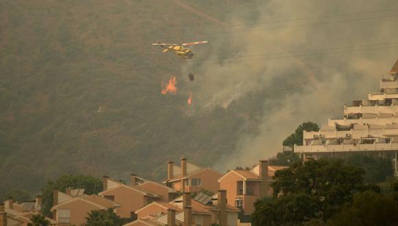 Un helicóptero sobrevuela un incendio forestal en Estepona, provincia de Málaga. (Foto: JORGE GUERRERO / AFP).