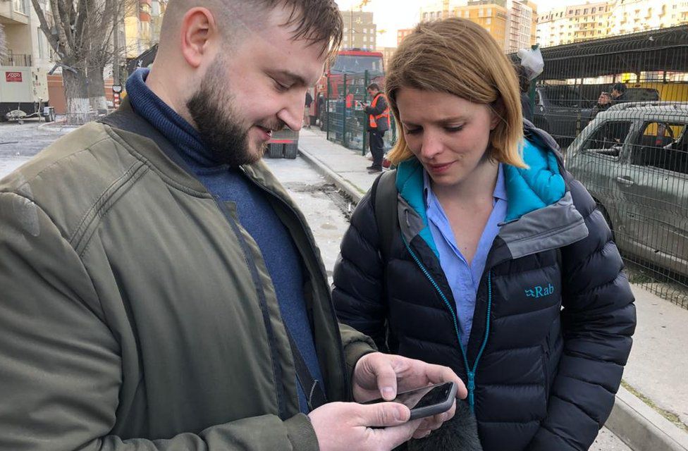 Yuriy looks at photos of his wife and daughter with our reporter.