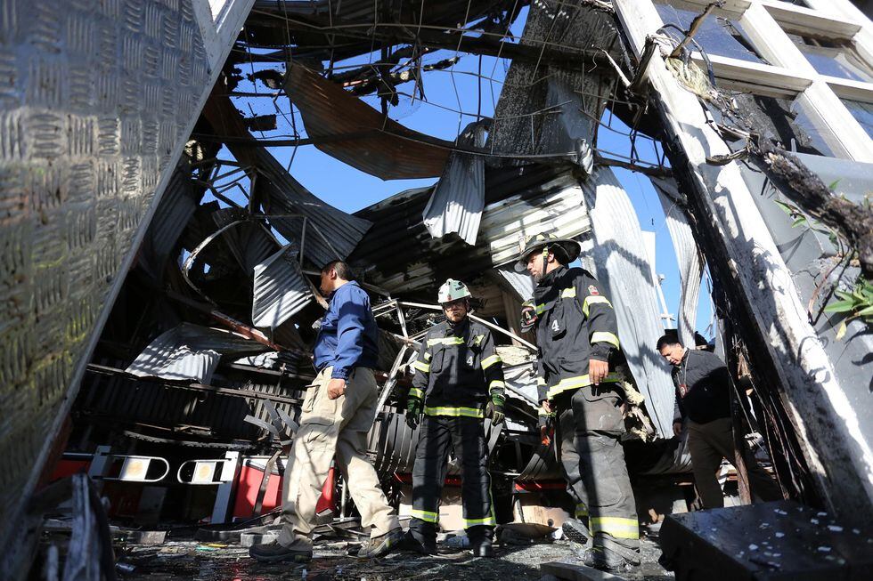 Personal policial y de bomberos inspecciona un supermercado en el que ocurrió una explosión después de ser saqueado e incendiado por manifestantes en Santiago. (EFE/ Elvis González).