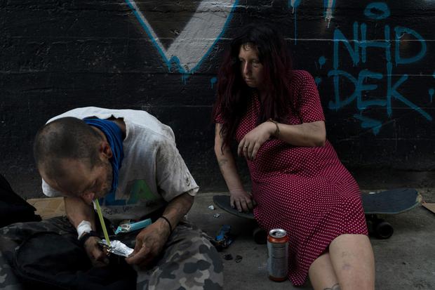 Jenn Bennett, que está drogada con fentanilo, se sienta en su patineta con un ojo morado visible mientras su amigo, Jesse Williams, fuma la droga en Los Ángeles, el martes 9 de agosto de 2022.(Foto AP/Jae C. Hong).