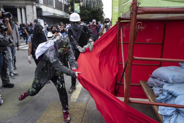 Manifestantes intentan arrancar una tela envuelta alrededor de un andamio con ira, durante una marcha exigiendo la renuncia del presidente Alejandro Giammattei, en la Ciudad de Guatemala. (AP/Moises Castillo).
