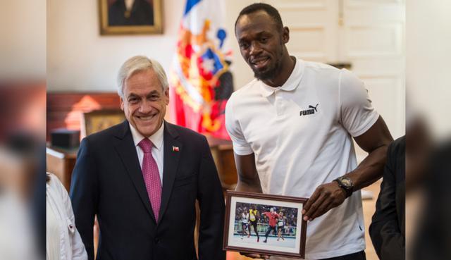 Usain Bolt posa junto al mandatario Sebastián Piñera y su curioso obsequio. (Foto: AFP)