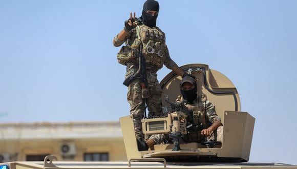 Los combatientes de las Fuerzas Democráticas Sirias (SDF) hacen un gesto mientras se dirigen a la línea del frente de Dhiban en la provincia de Deir Ezzor, el 4 de septiembre de 2023, durante una visita guiada a los medios organizada por las SDF. (Foto de Delil Souleiman / AFP)