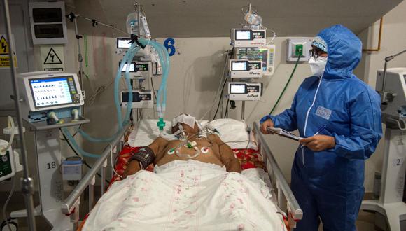 Un profesional de la salud atiende a un paciente de coronavirus en la Unidad de Cuidados Intensivos del hospital Vírgen de Fátima, que fue construido dentro de las instalaciones del estadio Campeones del 36, en Sullana, Piura, norte del Perú, el 19 de octubre de 2021. (ERNESTO BENAVIDES / AFP).