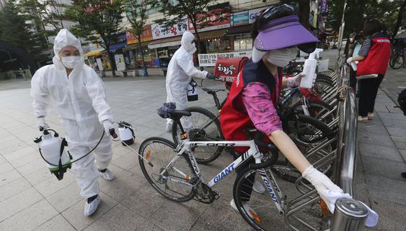 Trabajadores y voluntarios desinfectan bicicletas como medida de precaución contra el coronavirus en una calle en Goyang, Corea del Sur, el 25 de agosto de 2020. (AP Foto / Ahn Young-joon).