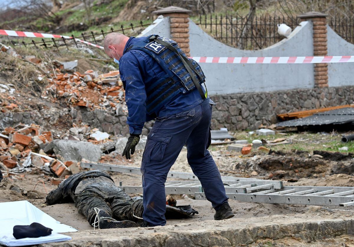 A Ukrainian rescuer inspects a body discovered in the sewer of a gas station outside the village of Buzova, west of kyiv, on April 10, 2022. (Sergei SUPINSKY / AFP)