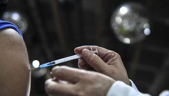 Una enfermera administra una dosis de la vacuna Moderna contra el COVID-19 a un hombre en un punto de vacunación del bar La Cantina de Medellín, el 11 de agosto de 2021. (JOAQUIN SARMIENTO / AFP).
