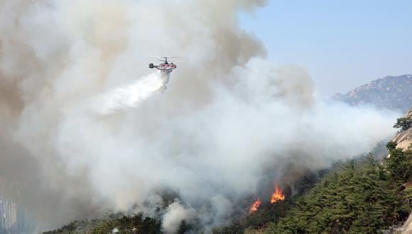 Un helicóptero de la Agencia Nacional de Bomberos arroja agua para contener un incendio en el Monte Inwang, Seúl, Corea del Sur, el 2 de abril de 2023. (Foto de EFE/EPA/YONHAP)