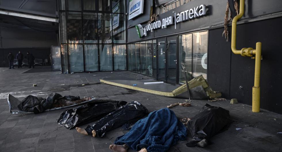 Los cuerpos de ucranianos cubiertos con mantas y bolsas de plástico afuera del centro comercial Retroville tras un ataque con misiles rusos en Kiev el 21 de marzo de 2022. (ARIS MESINIS / AFP).