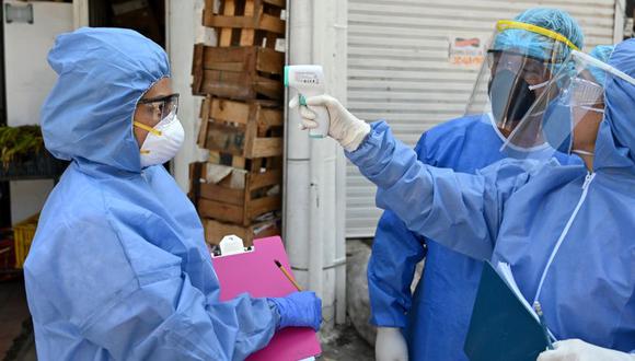 Coronavirus en Colombia | Ultimas noticias | Último minuto: reporte de infectados y muertos jueves 23 de abril del 2020 | Covid-19 | Un trabajador de la salud que usa un traje de bioseguridad toma la temperatura de una enfermera durante un chequeo del nuevo coronavirus en Colombia.