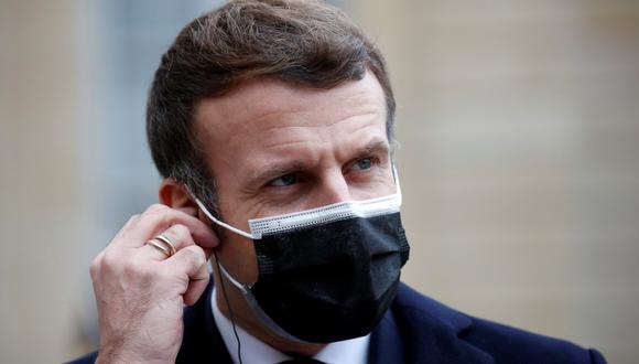 El presidente francés Emmanuel Macron, con una máscara protectora, ajusta sus auriculares mientras habla con los medios de comunicación en el Palacio del Elíseo en París, el 16 de diciembre de 2020. (REUTERS/Gonzalo Fuentes).