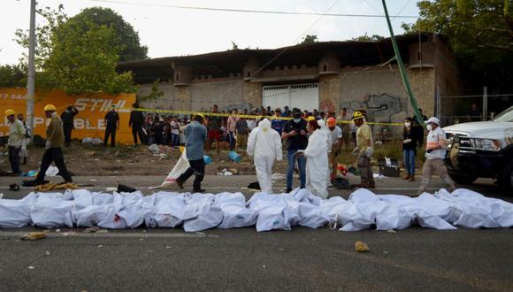 Técnicos forenses junto a cuerpos cubiertos con sábanas blancas alineados en el lugar de un accidente de tráiler que dejó al menos 49 personas muertas, la mayoría de ellos migrantes centroamericanos, en Tuxtla Gutiérrez, en el estado de Chiapas. México. (Foto: REUTERS / Jacob García).