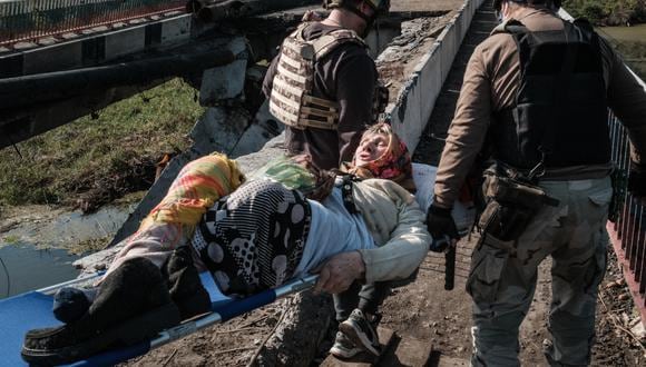 Dusya, de 86 años, es llevada en camilla por voluntarios para cruzar el puente roto sobre el río Oskil en Kupiansk, región de Kharkiv, el 29 de septiembre de 2022. (Foto de Yasuyoshi CHIBA / AFP)