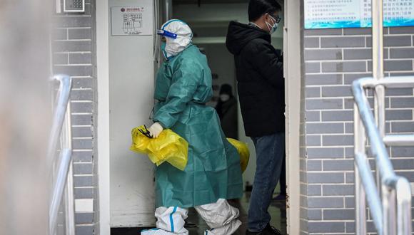 Una trabajadora de la salud con equipo de protección personal (EPP) transporta basura médica en una clínica de Beijing en medio de la pandemia de coronavirus. (Jade GAO / AFP).