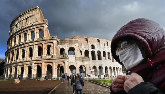Un hombre utiliza una máscara protectiva frente al Coliseo romano, uno de los múltiples monumentos históricos que han sido clausurados por la expansión del coronavirus en Italia. (Foto: AFP)