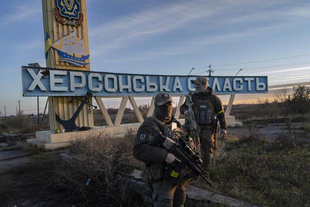 Two members of the Ukrainian Defense Forces stand next to a banner "Kherson region"Monday, Nov. 14, 2022. (AP Photo/Bernat Armangue).