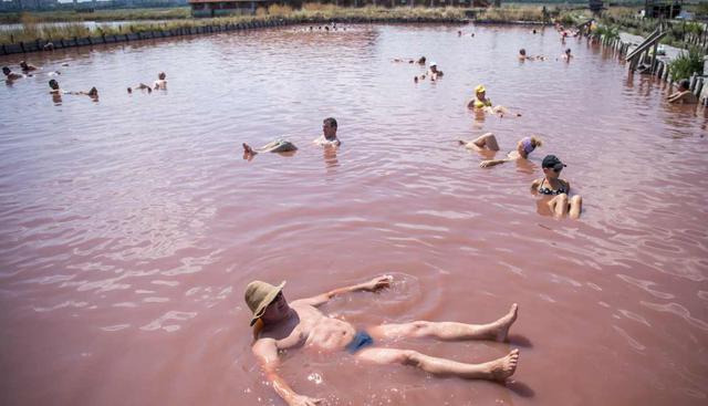 La gente descansa en los lagos de las salinas cerca de la ciudad de Burgas en el Mar Negro, Bulgaria. Miles de turistas visitan los lagos de sal roja para tomar baños de lodo. (Foto: AFP)
