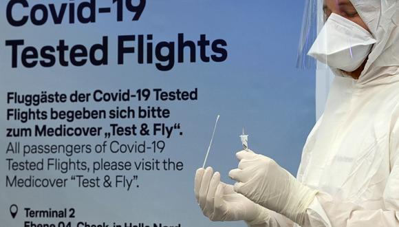 El personal sanitario sostiene un tubo de ensayo en la entrada del nuevo centro de pruebas de coronavirus de Lufthansa en el aeropuerto Franz-Josef-Strauss de Múnich, en el sur de Alemania. (Christof STACHE / AFP).