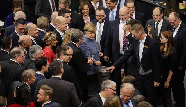 German Chancellor Angela Merkel, center, casts her vote at a voting on German forces international missions at the German parliament Bundestag in Berlin, Tuesday, Dec. 12, 2017. (AP Photo/Markus Schreiber)