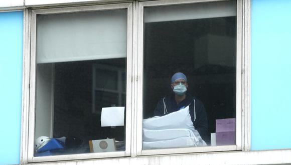 Un trabajador del hospital mira por la ventana mientras las enfermeras se reúnen frente al Hospital Mount Sinai en Manhattan el 16 de marzo de 2021.(Foto de TIMOTEO A. CLARY / AFP)