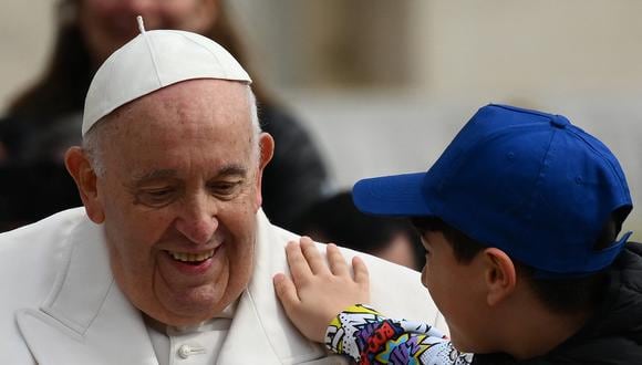 Un niño le da una palmadita en el hombro al papa Francisco mientras se marcha en el auto papamóvil el 29 de marzo de 2023 al final de la audiencia general semanal en la plaza de San Pedro en el Vaticano. (Foto de Vincenzo PINTO / AFP)
