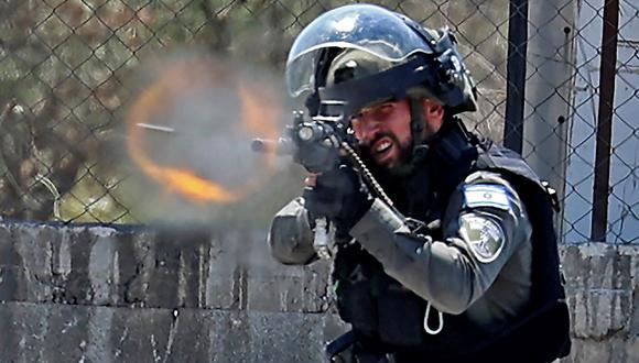 Un miembro de la policía fronteriza de Israel dispara balas de goma hacia los manifestantes palestinos, durante los enfrentamientos en la ciudad cisjordana de Beita, al sur de Naplusa, el 3 de junio de 2022. (JAAFAR ASHTIYEH / AFP).