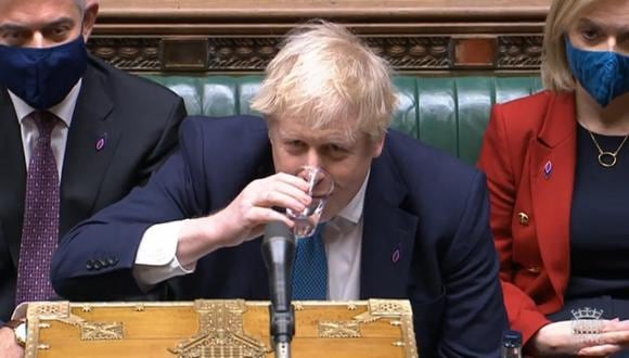 El primer ministro británico Boris Johnson toma agua durante la sesión de preguntas en la Cámara de los Comunes en Londres, Gran Bretaña, el 26 de enero de 2022. (EFE).