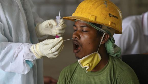 Un trabajador de la salud toma una muestra de un hisopo a una persona para una prueba de coronavirus Covid-19 en una obra de construcción en Nueva Delhi, India. (Foto de Prakash SINGH / AFP).