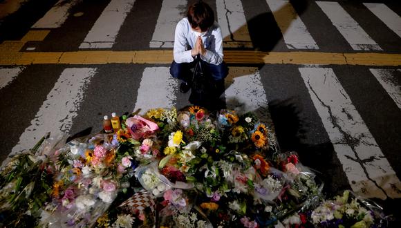 Nara. Una persona reza por Abe al frente de un arreglo floral. REUTERS