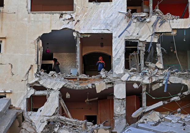 Palestinian women survey the damage inside an apartment in a badly damaged building in Gaza City. (Photo by MOHAMMED ABED / AFP).