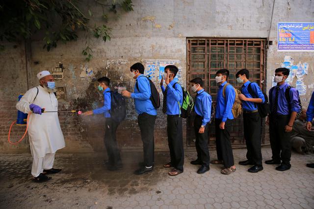 Personal del colegio rocía con desinfectante a los estudiantes a su llegada a su primer día de clase tras suspenderse debido al coronavirus, en Peshawar, Pakistán. (Foto: BILAWAL ARBAB / EFE)