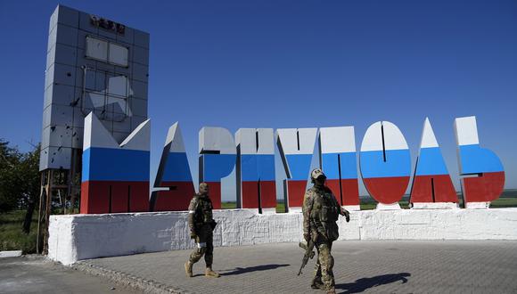 Soldados rusos pasan frente a un nombre de ciudad repintado con los colores de la bandera rusa en la entrada de Mariúpol. (Foto: AP)