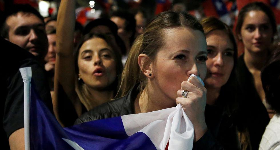 Una mujer besa una bandera de Chile mientras personas que rechazan la nueva Constitución celebran tras conocer los resultados del plebiscito. (CLAUDIO REYES / AFP).