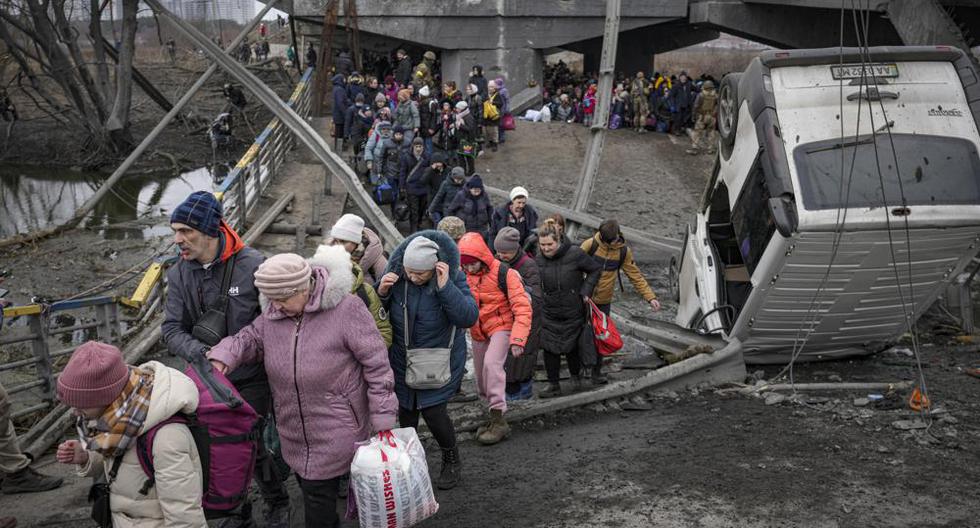 Las personas cruzan por un camino improvisado debajo de un puente que fue destruido por un ataque aéreo de Rusia, mientras huyen de la ciudad de Irpin, Ucrania, el sábado 5 de marzo de 2022. (Foto AP/Vadim Ghirda).