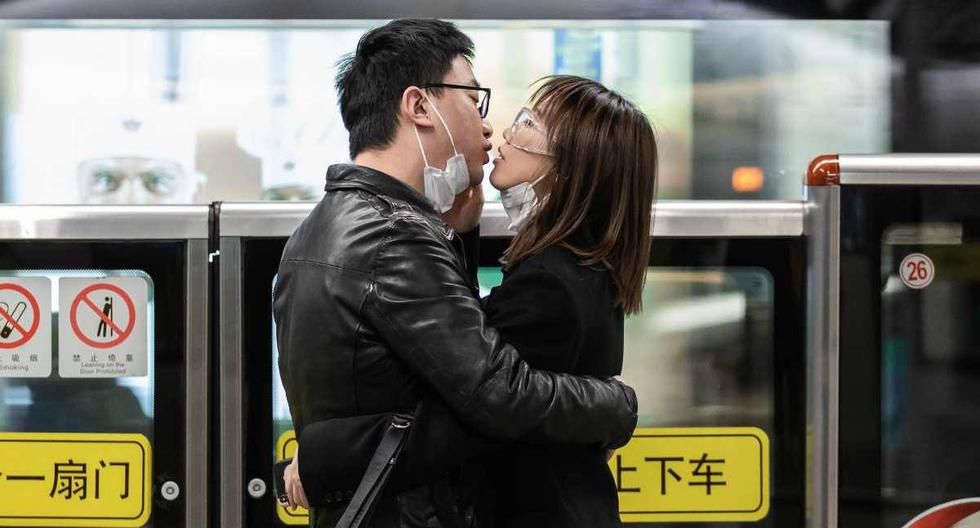 Una pareja se quita las mascarillas de seguridad y se besa mientras espera el transporte público en Shanghái. (Foto: EFE/EPA/LIU XINGZHE)