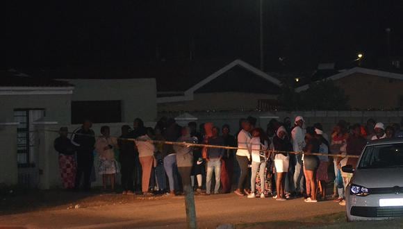 Los transeúntes esperan detrás de una cinta policial que marca la escena de un tiroteo masivo en Gqeberha, Sudáfrica, el 29 de enero de 2023. (Foto: Luvuyo Mehlwana / AFP)
