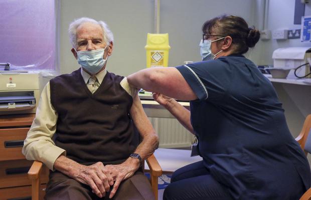 El paciente Brian Horne recibe una dosis de la vacuna Pfizer-BioNtech COVID-19 de la enfermera principal Helen Ellis Steve en el oeste de Londres, Reino Unido, el 14 de diciembre de 2020. (Steve Parsons / POOL / AFP).