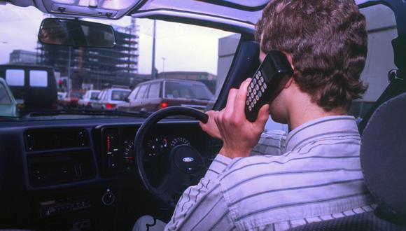 Hombre conduciendo mientras usa el teléfono integrado en el automóvil 1990. Creador: Desconocido. (Photo by National Motor Museum/Heritage Images via Getty Images)