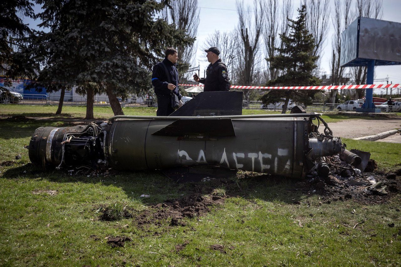Ukrainian police inspect the remains of a large rocket with the words 