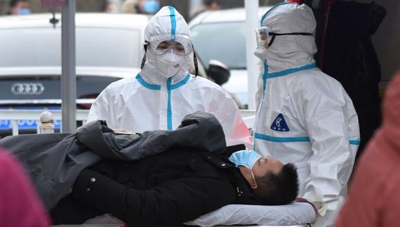 Trabajadores médicos que usan trajes protectores como precaución contra el coronavirus COVID-19 llevan a un paciente a la clínica de fiebre en un hospital en Beijing. (Foto: AFP / GREG BAKER).