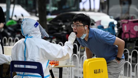 Un trabajador de la salud obtiene una muestra de hisopo de un hombre para que le hagan la prueba del coronavirus Covid-19 en Beijing, China, el 10 de junio de 2022. (Jade GAO / AFP).