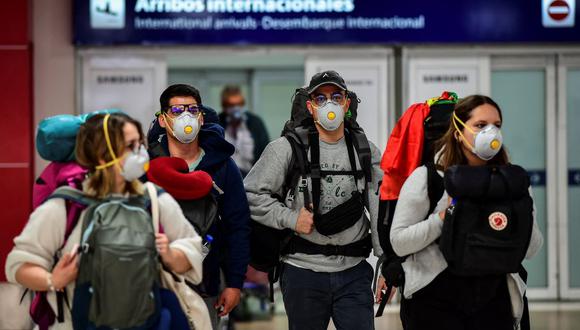 Pasajeros con mascarilla como medida preventiva contra la propagación del coronavirus COVID-19 arriban al Aeropuerto Internacional de Ezeiza en Buenos Aires, Argentina, el 12 de marzo de 2020. (RONALDO SCHEMIDT / AFP).