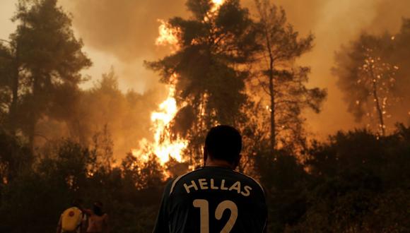 Un residente local, con la camiseta de la selección nacional de fútbol de Grecia, observa las llamas que se acercan, durante un incendio forestal en el pueblo de Pefki en Evia, Grecia. (Foto: EFE/ KOSTAS TSIRONIS)