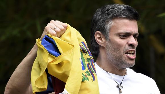 Leopoldo López muestra una bandera de Venezuela mientras saluda a los partidarios que se reunieron fuera de su casa en Caracas el 8 de julio de 2017. (Foto por Juan BARRETO / AFP).