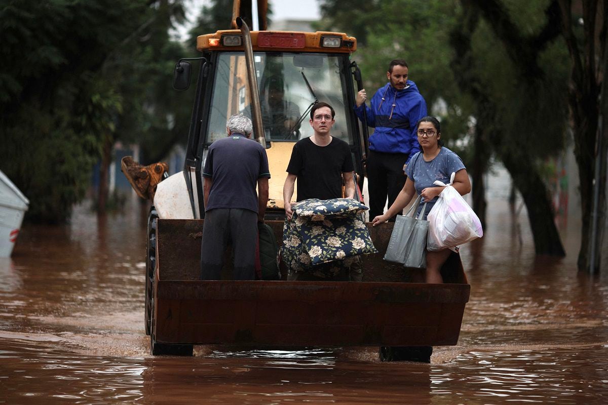 People are evacuated from a flooded area in a skid steer in the São Geraldo neighborhood, in Porto Alegre, Rio Grande do Sul, Brazil, on May 4, 2024. (Photo by Anselmo Cunha / AFP)