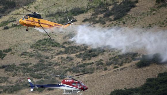 Dos helicópteros pasan mientras luchan contra un incendio forestal en Springville.