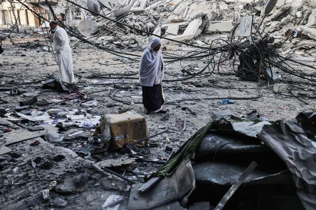Palestinians walk after performing Eid al-Fitr prayers amid the rubble near al-Sharouk tower, which housed the office of the Al-Aqsa television channel in the Gaza Strip. (Photo by MOHAMMED ABED / AFP).