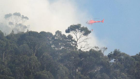 Un helicóptero, que utiliza el sistema Bambi bucket, arroja agua entre el humo que se observa hoy en los cerros orientales en Bogotá (Colombia). EFE/ Carlos Ortega