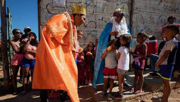 Hombres vestidos de Reyes Magos entregan refrigerios a niños en un caserío dentro del Cementerio General del Sur en Caracas (Venezuela). (Foto: EFE/ Rayner Peña R.).